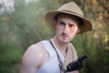Fototapeta premium Adventurer man with the handgun in the jungle thicket concept.