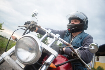 Fototapeta na wymiar Motorcyclist is sitting on the motorbike outdoors.