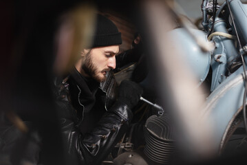 Obraz na płótnie Canvas Man in the leather jacket works in the motorbike workshop concept.