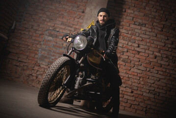 Fototapeta na wymiar Motorbiker in the black leather jacket sits on the old motorbike concept.