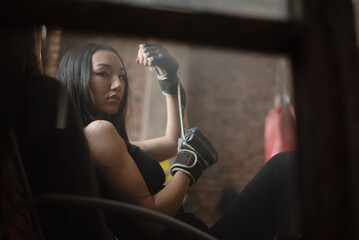 A young sporty girl putting on boxing gloves close up.