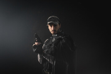 A man with the airsoft rifle in the smoke on the dark background. Special agent concept. Action movie film concept.