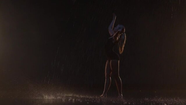 Sensual Young Woman Dancer Performing in the Rain in Dark Studio