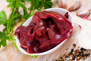Fresh raw rabbit liver with seasonings on wooden background. Dietary meat product