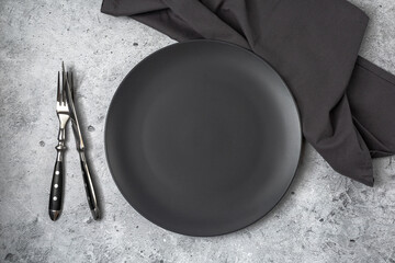 Empty black slate plate on grey stone table and napkin. Food background for menu, recipe. Table...