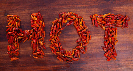 Word HOT is laid out of many cayenne peppers on a wooden table