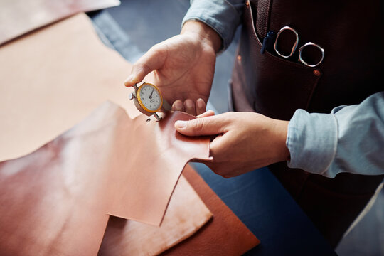 Close up of artisan inspecting leather thickness in workshop, copy space