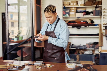 Waist up portrait of modern artisan working with leather in shop, copy space