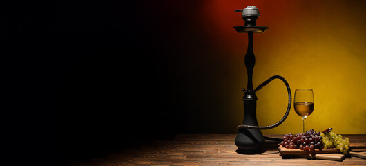 Hookah with grapes and wine on table against dark background