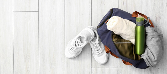 Sports bag and shoes on wooden background with space for text, top view
