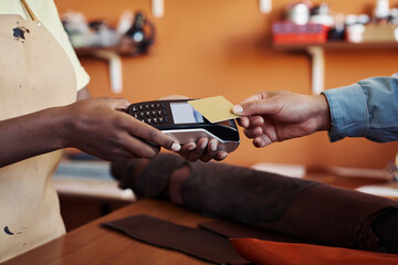 Side view close up of unrecognizable young woman holding banking terminal with client paying by...