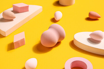 Makeup sponges with decor on yellow background