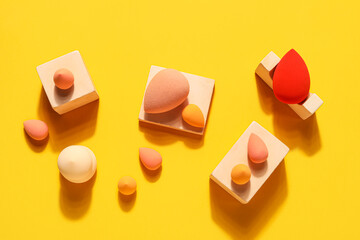 Makeup sponges with decor on yellow background