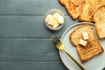 Plate with toasts and bowl of butter on dark wooden background