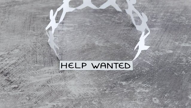 staff shortages and business struggling after the pandemic, peper people chain with Help Wanted text on gray background