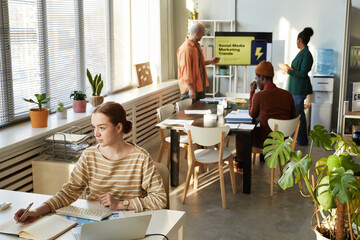 Wide angle view at creative young people working in office with focus on woman at workplace, copy space