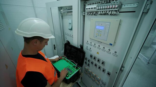 Electrical engineer working check the electric current voltage and overload at front of load center cabinet or consumer unit for maintenance in main power distribution system room.