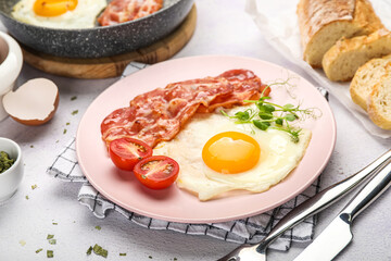 Plate of tasty fried egg with bacon on light table