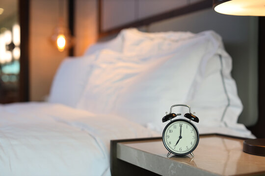 7 O’clock alarm clock picture in bedroom with bed blurred image background