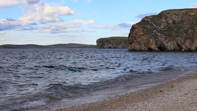 Baikal Lake on a windy August evening. The sandy beach of the Small Sea and the rocky shore of Olkhon Island. Waves of clear water near the shore. Natural background. Beautiful seascape