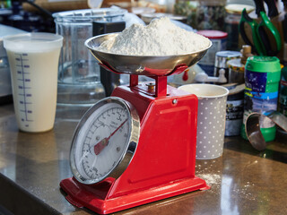 Weighs flour on manual pie scale in home kitchen