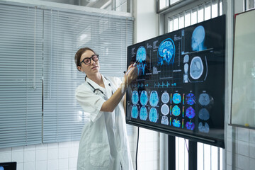 Medical scientists presenting in the brain research laboratory by monitor showing MRI, CT scans...