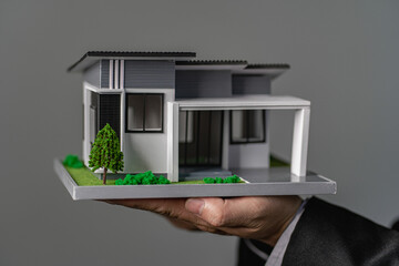 home insurance concept businessman holding a small house model in hand