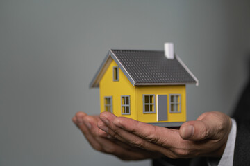 Fototapeta na wymiar home insurance concept businessman holding a small house model in hand