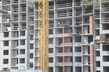 Full-color horizontal photo. Urban landscape. Part of the facade of a building under construction. Geometric linear composition with windows.