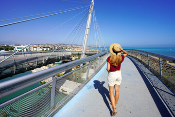 Young woman walking on Pescara modern bridge enjoying seascape from promenade in Abruzzo region,...