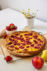 Fragrant homemade strawberry-apple pie. homemade baking. Hands in the frame holding a grill with a pie. Front view. Copy space