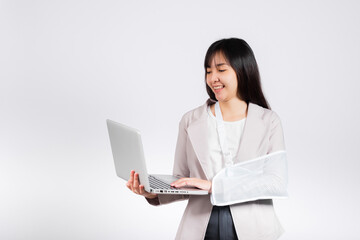 Asian business woman confident smiling broken arm after accident and wear arm splint for treatment but still have to work she hold laptop computer studio isolated on white background,copy space