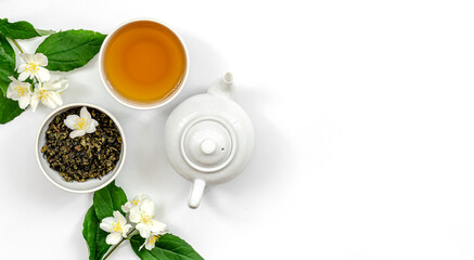 Obraz na płótnie Canvas jasmine tea in a cup and kettle for dietary nutrition, jasmine branches with flowers in the corners of the frame, top view, banner