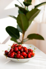 A bowl of sweet cherries on a white table