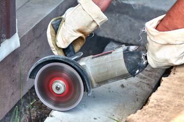 A worker with a circular saw cuts a concrete block in close-up.