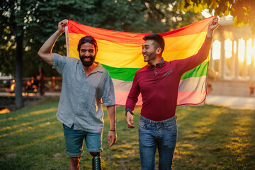 Bisexual male couple outdoors with rainbow flag