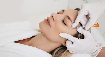 Obraz na płótnie Canvas Beautiful woman during facial mesotherapy for smoothing of mimic wrinkles around eyes with beautician. Anti-aging injections for rejuvenation and lift skin