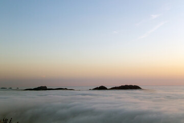 Obraz premium Las Islas Cíes sobresalen sobre un mar de niebla al atardecer. Ría de Vigo, Galicia, España.