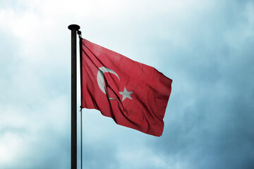 Flag of Turkey is under dark cloudy sky, close up