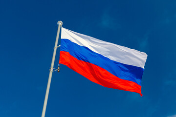 The national flag of Russia is under blue sky