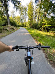 Fototapeta na wymiar First-person view cycling in the forest. Close-up of a mountain bike handlebar. Summertime outdoor leisure sport activity concept.