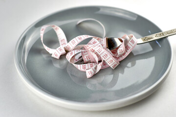 a measuring tape wound on a fork on a plate diet concept