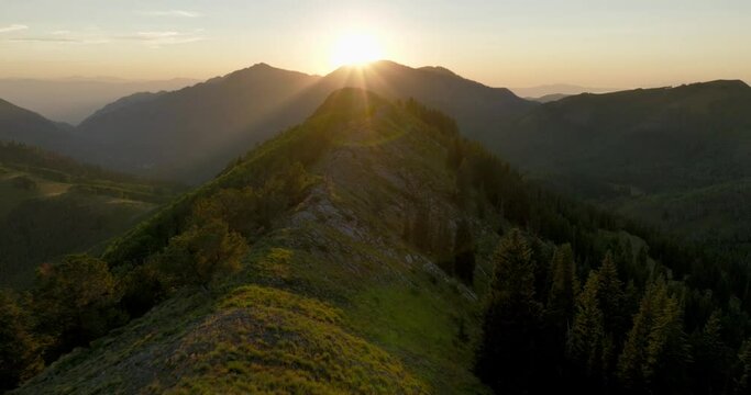 Aerial FPV over backcountry mountain range and forest at sunset.