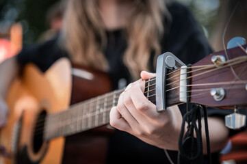 Close-up of woman playing guitar. Hand of woman playing guitar on the street.