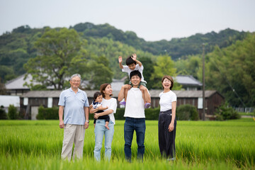 夏休み　故郷に帰省した三世代家族の集合写真　田舎のあぜ道で撮影