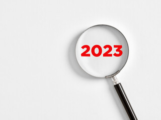 Magnifying glass magnifies the year 2023 on white background. Focusing on the year 2023 for...