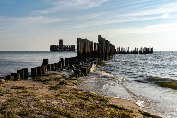 Old ruined wooden pier and a sandy beach	