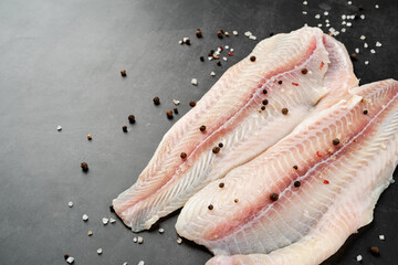 Raw pangasius fish fillet with spice on concrete background