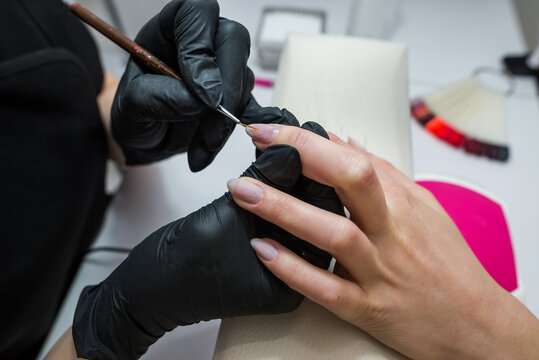 The manicurist covers the client's nails with red varnish. Manicure in a beauty salon.