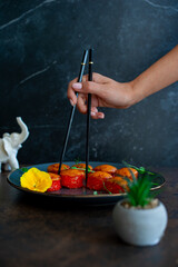 Sushi roll is taken with chopsticks